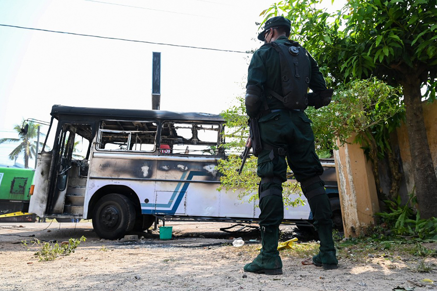 A soldier guards an area next to a burnt-out bus near the Sri Lankan president's home in Colombo on April 1, 2022. - Security forces were deployed across the Sri Lankan capital on April 1 after protesters tried to storm the president's home in anger at the nation's worst economic crisis since independence. (Credit: Ishara S. KODIKARA / AFP)