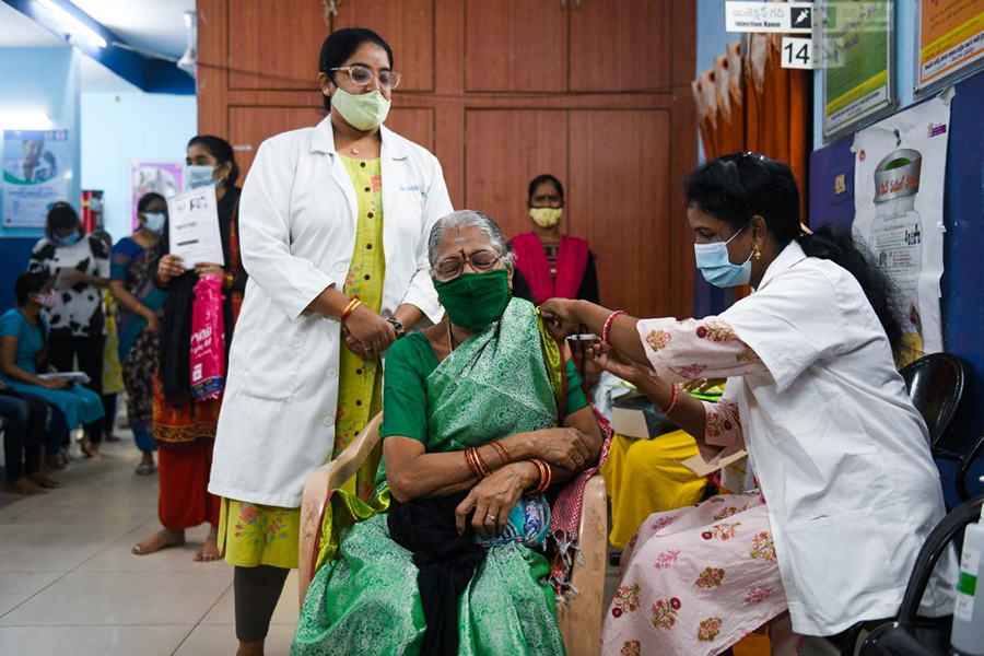 A health worker inoculates a woman with a third 'booster' dose of the Covid-19 coronavirus vaccine in Hyderabad on January 10, 2022, as the country sees an Omicron-driven surge in cases. (Credit: Noah SEELAM / AFP)