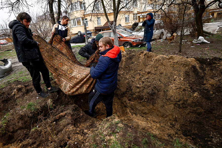 Serhii Lahovskyi, 26, and other residents carry the body of Ihor Lytvynenko to bury him at the garden of residential building​. According to residents, Ihor was killed by Russian soldiers beside a building's basement, amid Russia's invasion of Ukraine, in Bucha, Ukraine April 5, 2022. (Credit: Zohra Bensemra / Reuters)

