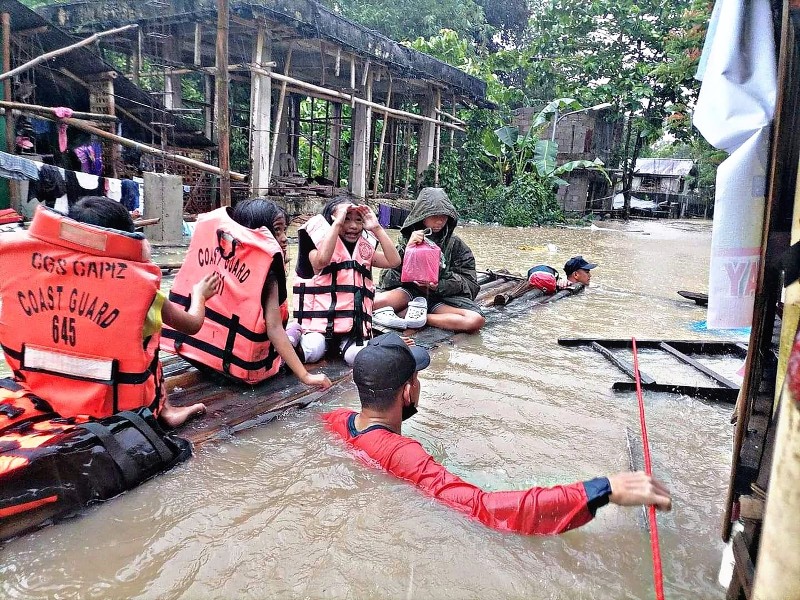 A coast guard personnel evacuating local residents from their flooded homes on a makeshift raft in the town of Panitan, Capiz province as heavy rains brought on by Tropical Storm Megi inundated the area. (Credit: AFP)

