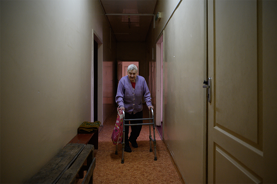 An elderly woman walks in a hallway at the Mercy House shelter for people in need, on the outskirts of Dnipro on April 15, 2022. The elderly are 