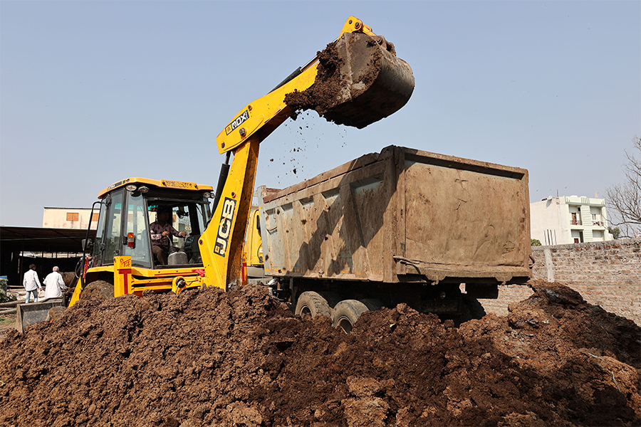 In this photograph taken on March 4, 2022, an excavator loads cow dung for biogas production into a truck at the dairy farm of farmer Suresh Sisodia in Mayakhedi village on the outskirts of Indore. India is tapping a new energy source that promises to help clean up smog-choked cities and is already providing a vital revenue stream for poor Indian farmers: truckloads of bovine manure. (Credit: Gagan NAYAR / AFP)