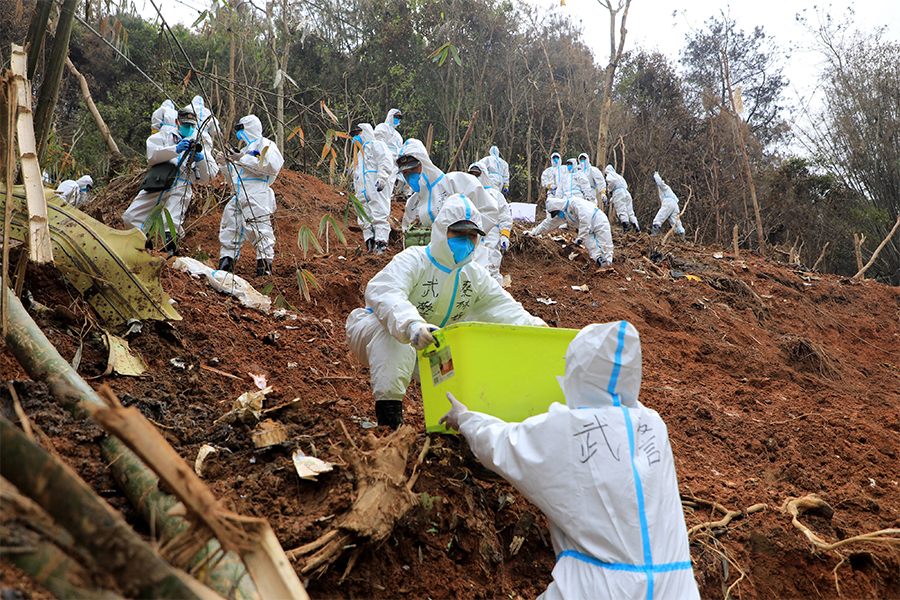 This photo taken on March 26, 2022 shows paramilitary police officers transferring fragments of wreckage of the China Eastern passenger jet which crashed onto a mountainside in Tengxian county, Wuzhou city, in China's southern Guangxi region. The Boeing 737-800 was flying between the cities of Kunming and Guangzhou on March 21 when it nosedived into a mountainside, disintegrating on impact and killing all 132 people on board.