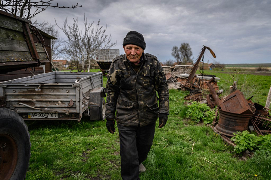 Vasili Kushch walks through a farmyard amid the sound of regular nearby shelling, in the village of Mala Tokmatchka which he refuses to leave saying he has nowhere to go and that no one will take him because he is a farm worker, near the southern front of fighting between Ukrainian and Russian forces, south of Zaporizhzhia on April 23, 2022. (Credit: Ed JONES / AFP)