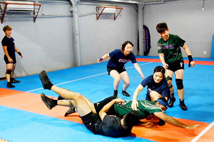 This picture taken on May 23, 2022 shows participants playing kabaddi, a tag-wrestling sport popular in South Asia which involves players trying to tag an opponent on the rival's side before making it back to their own half, in Hong Kong. Overlooked by high-rises on the outskirts of Hong Kong, a group of students practise body-slam tackles and vicious ankle-wrenches at weekly training for an unlikely sport: the ancient Indian game of kabaddi. Image: Peter PARKS / AFP

