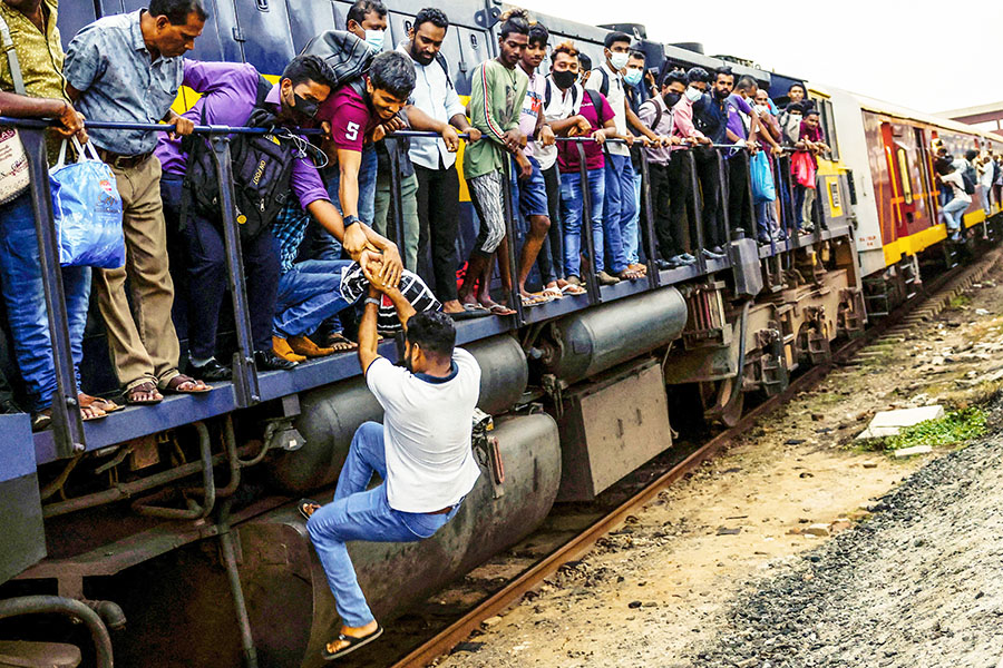 A passenger is helped to get on the engine of an overcrowded train in Colombo, Sri Lanka, July 6, 2022. Amid Sri Lanka's economic crisis, public transport is being disturbed due to a massive fuel shortage.  Image: Reuters/Dinuka Liyanawatte 
