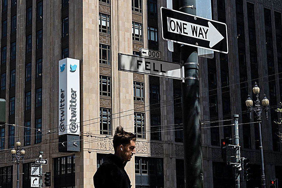 In this file photo taken on April 26, 2022 a person walks past the Twitter headquarters in downtown San Francisco, California. Elon Musk pulled the plug on his deal to buy Twitter on July 8, 2022, accusing the company of 