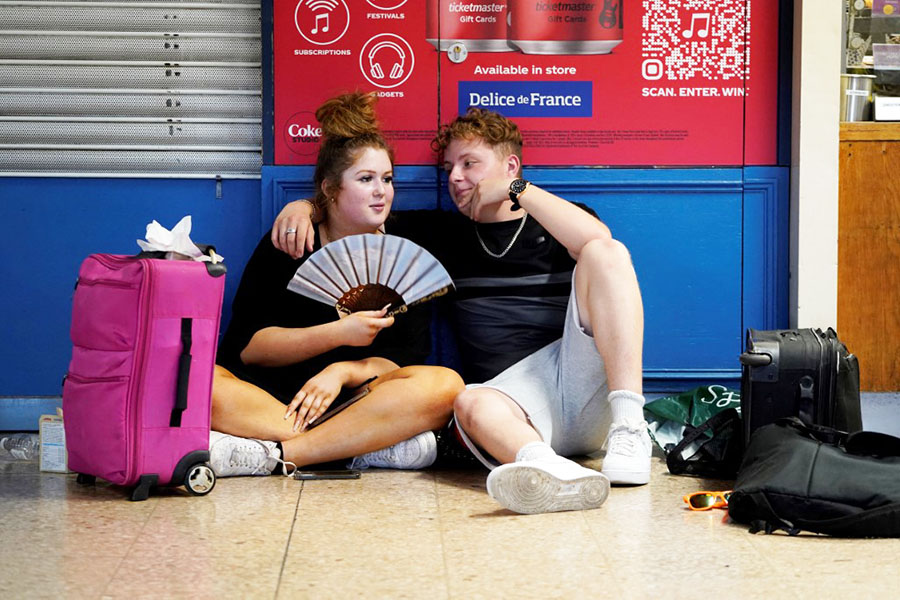 A rail passenger uses a fan to cool down as they sit with their belongings at Euston train station in central London, on July 19, 2022, as services were cancelled due to a trackside fire, and as the country experiences an extreme heat wave.
Image: Niklas Halle'n / AFP