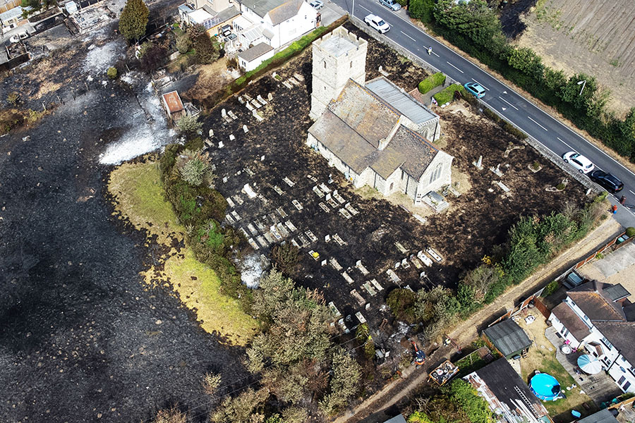 WENNINGTON, GREATER LONDON - JULY 20: An aerial view shows the scorched graveyard around a church following a large blaze the previous day, on July 20, 2022 in Wennington, Greater London. A series of fires broke out across England yesterday as the UK experienced a record-breaking heatwave. Temperatures in many places reached 40c and over. Image: Leon Neal/Getty Images