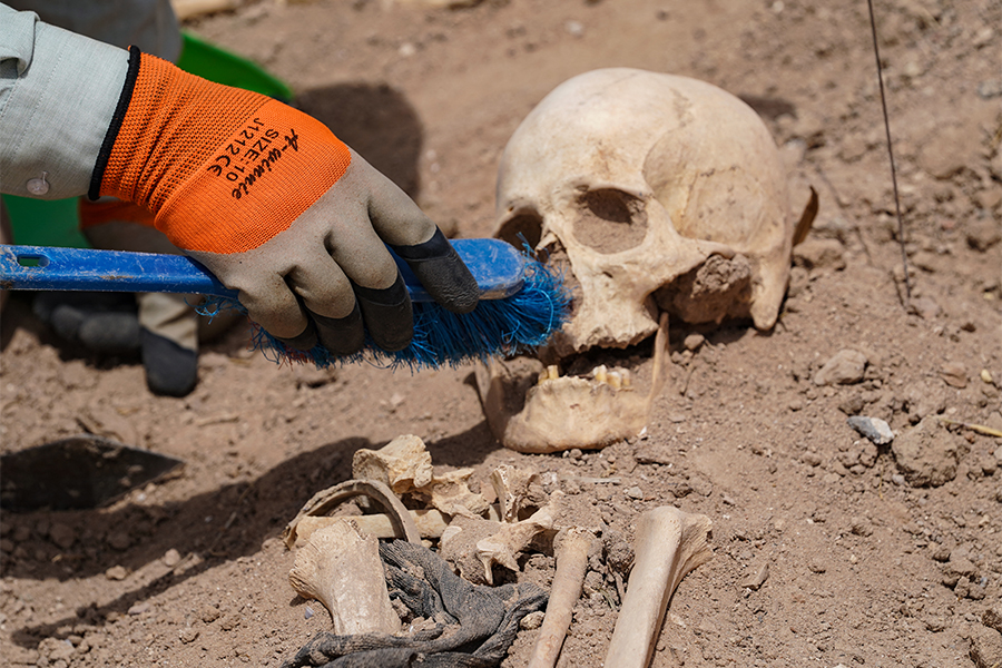 A forensics expert uses a brush to exhume a skull at the site of a mass grave, discovered by chance when property developers wanted to prepare the land for construction, in the central city of Najaf, on May 18, 2022. Photo: Qassem al-KAABI / AFP