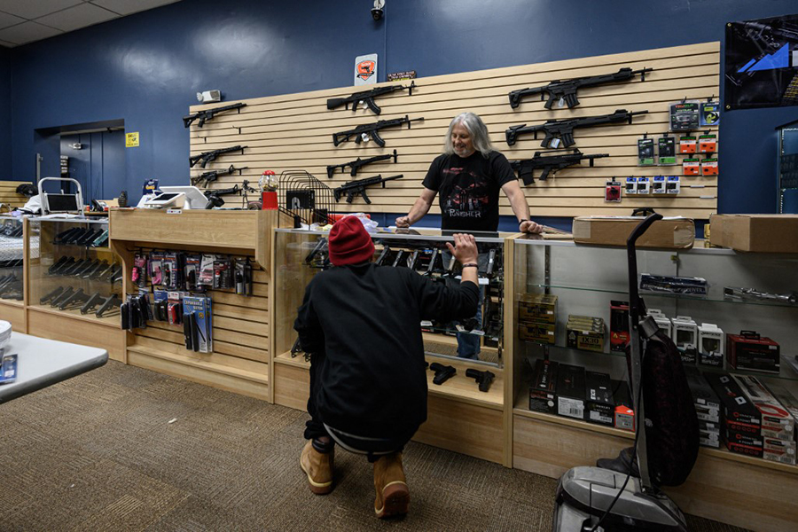 An customer browses guns at RTD Arms & Sport in Goffstown, New Hampshire on June 2, 2022. Smaller gun makers are booming in the US , thanks to ravenous and sometimes specialized demand for pricey limited-production pistols and custom rifles, engraved with bible passages or the US flag. The millions of guns produced annually in the US are primarily made by the nation's biggest manufacturers, yet smaller operators have poured into a market that saw production nearly triple from 2000 to 2020. Image: Ed JONES / AFP