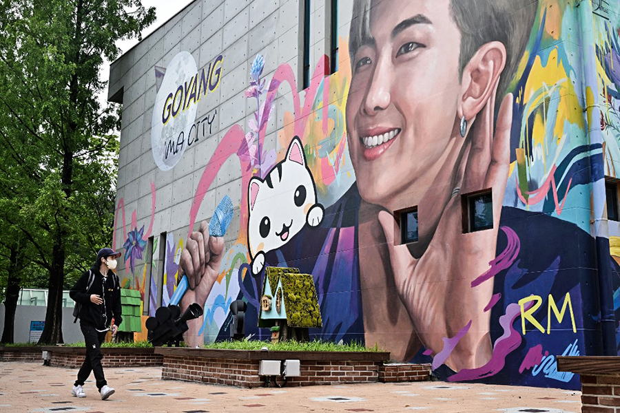 A man walks past a mural depicting RM, a member of K-pop group BTS, in Goyang, northwest of Seoul, on June 15, 2022. (Photo by Anthony WALLACE / AFP)