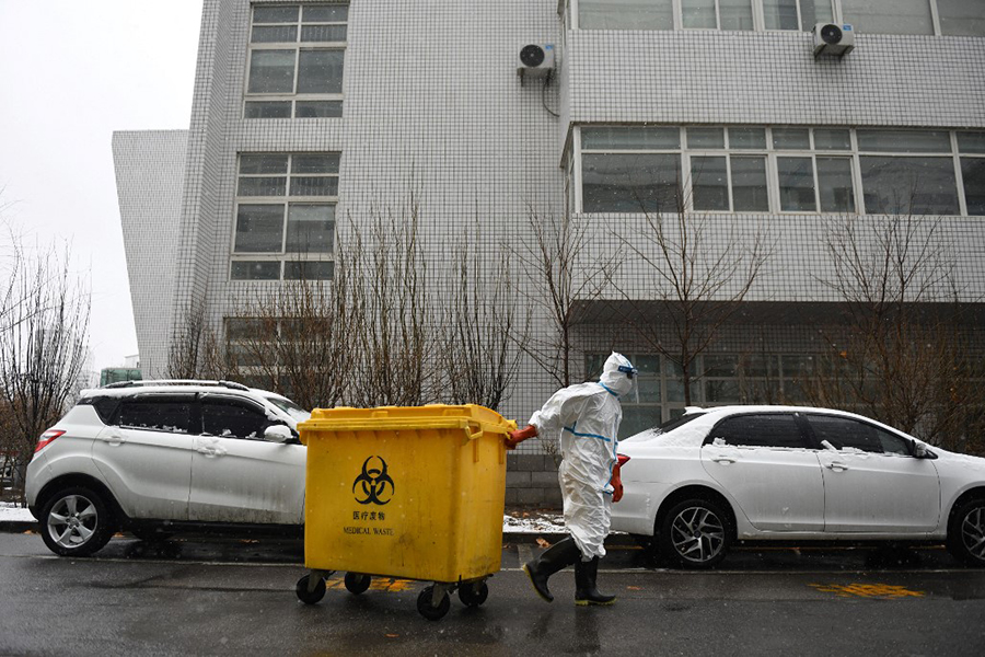 In this file photo taken on February 14, 2020, a worker carts a bin loaded with medical waste at the Youan Hospital in Beijing. Hazmat-suited workers poke plastic swabs down millions of throats in China each day, leaving bins bursting with medical waste that has become the environmental and economic levy of a zero-Covid strategy. Image: Greg Baker / AFP