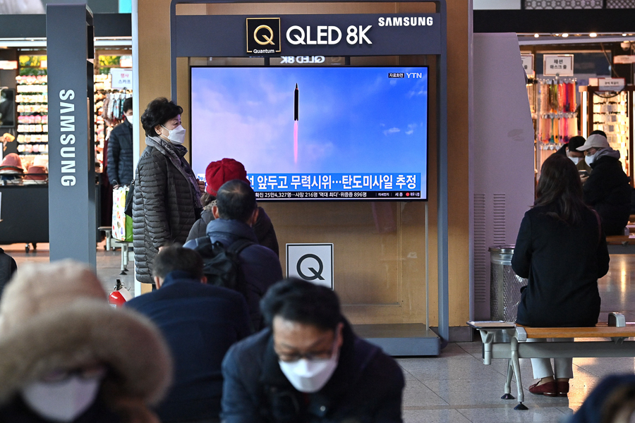 People watch a television screen showing a news broadcast with file footage of a North Korean missile test, at a railway station in Seoul on March 5, 2022, after North Korea fired at least one 
