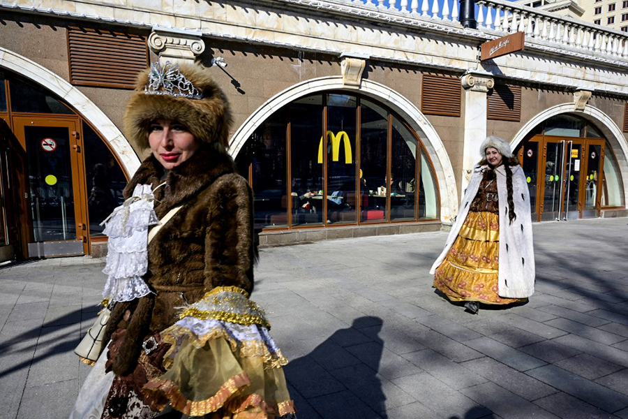 Women walk in front of a McDonald's restaurant in central Moscow on March 9, 2022. McDonald's, Coca-Cola and Starbucks on March 8, 2022 bowed to public pressure and suspended their operations in Russia, joining the international corporate chorus of outrage over Moscow's invasion of Ukraine. Several of these companies, symbols of American cultural influence in the world, have been the subject of boycott calls on social media as investors have also begun to ask questions about their presence. (Credit: AFP)​