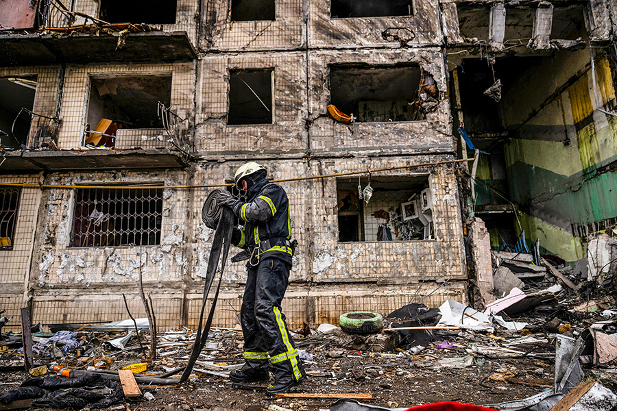 Emergency workers extinguish flames and help residents after their apartment building in the Obolon district of Kyiv, Ukraine, was struck by artillery shells on Monday, March 14, 2022. With civilian areas coming under fire and an estimated half the population having fled, the avenues of the Ukrainian capital, under siege by Russian forces, are almost deserted. (Lynsey Addario/The New York Times)