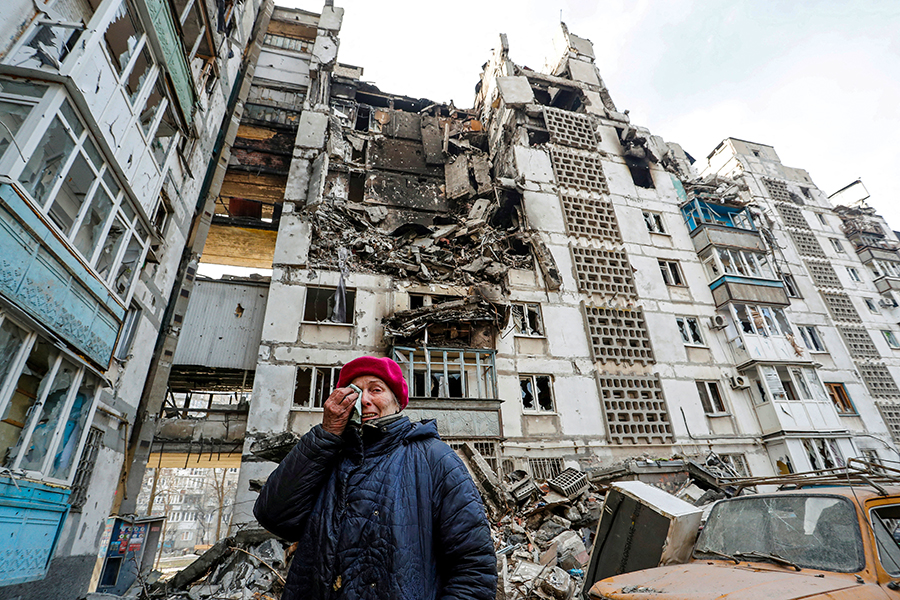 Local resident Valentina Demura, 70, reacts next to the building where her apartment, destroyed during Ukraine-Russia conflict, is located in the besieged southern port city of Mariupol, Ukraine March 27, 2022. Valentina worked for many years at the Azovstal Iron and Steel Works. After her apartment was destroyed, she lives with neighbors in their apartment, and they take shelter together in the basement. Image: Alexander Ermochenko / Reuters    