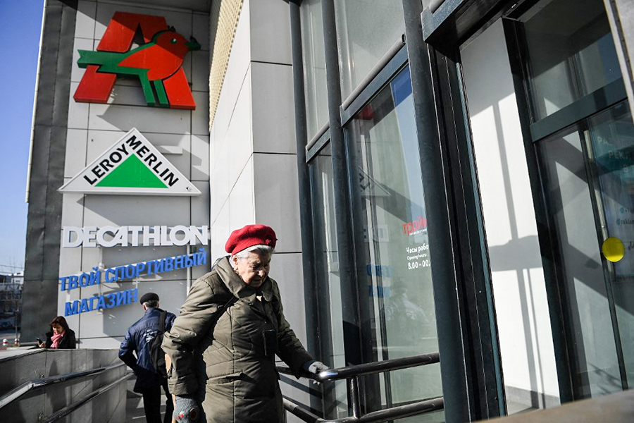 An elderly woman enters a shopping centre housing an Auchan supermarket, a Leroy Merlin DIY store and a store of French sports goods retailer Decathlon in Moscow on March 24, 2022. Image: NATALIA KOLESNIKOVA / AFP