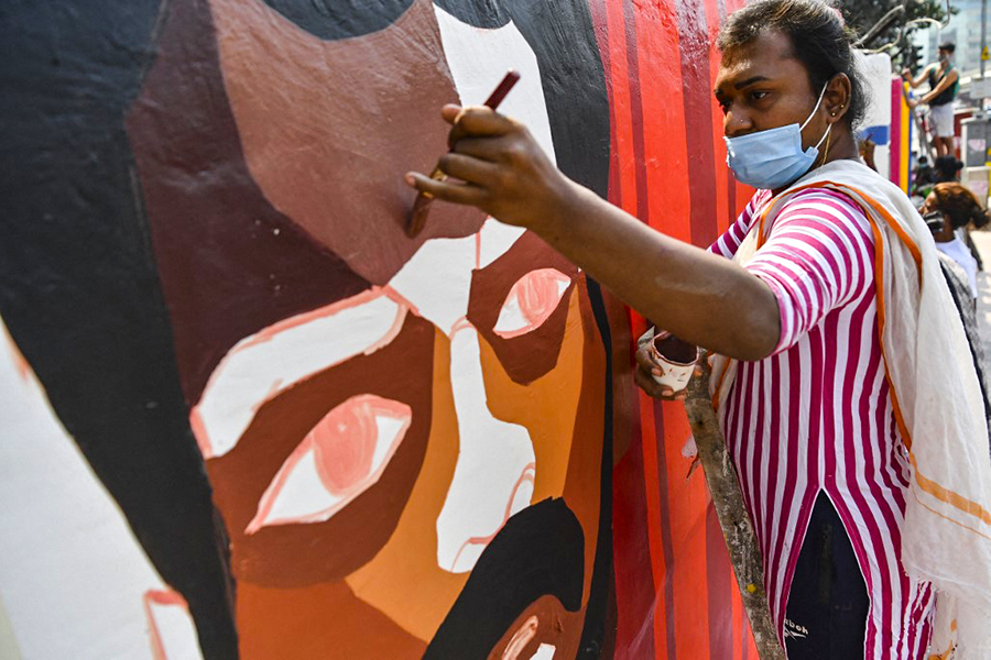 
 A member of the transgender community and of the of Aravani Art Project, a women and trans-women art collective, paints a mural in a wall along a street in Mumbai. Image: Indranil Mukherjee / AFP