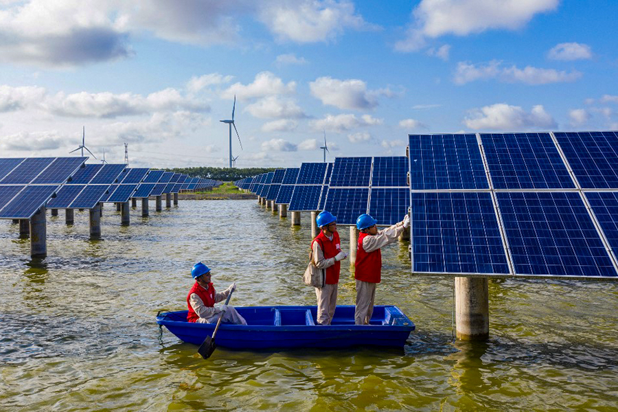This photo taken on July 19, 2021 shows electrical workers in a boat as they check solar panels at a photovoltaic power station built in a fishpond in Haian in China's eastern Jiangsu province. (Credits: AFP / China OUT)
