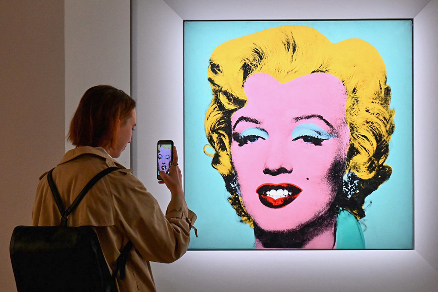 In this file photo taken on April 29, 2022 a woman takes a photo of Andy Warhol's 'Shot Sage Blue Marilyn' during Christie's 20th and 21st Century Art press preview at Christie's New York in New York City. - An iconic portrait of Marilyn Monroe by American pop art visionary Andy Warhol went under the hammer for a record 5 million on May 9, 2022 at Christie's, becoming the most expensive 20th century artwork ever sold at public auction.
