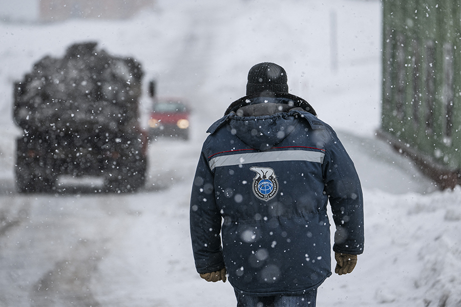 A man wearing an anorak with the logo of Arktikugol company on the back walks in the blizzard on May 7, 2022, in the miners' town of Barentsburg, on the Svalbard Archipelago, northern Norway.​ (Credits: Jonathan NACKSTRAND / AFP)

