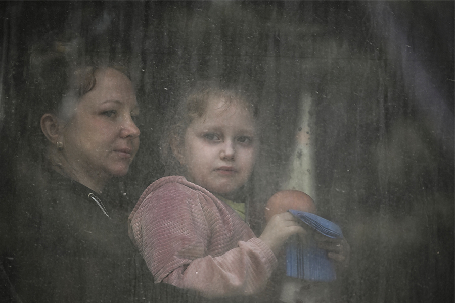 A mother with her daughter sit inside a bus as they evacuate the city of Bakhmut in the eastern Ukranian region of Donbas on May 22, 2022, amid Russian invasion of Ukraine.​ (Credits: ARIS MESSINIS / AFP)

