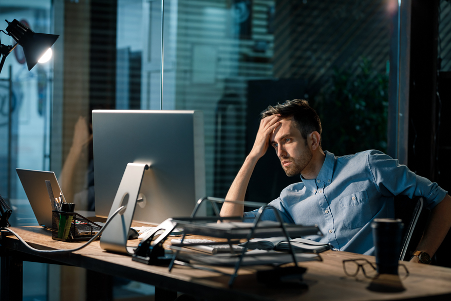 It is an image of a frustrated employee looking at a computer screen. Saying no to your superior can be essential for maintaining a healthy balance at work.