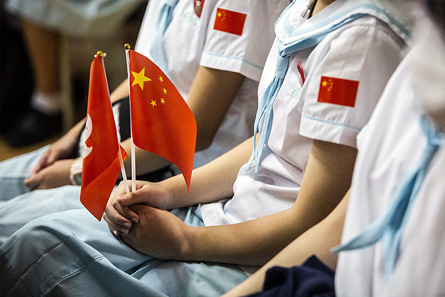 In this file photo taken on October 1, 2021, a student holds a Chinese and Hong Kong flag during a flag-raising ceremony to mark China's National Day at a school in the Tung Chung district of Hong Kong. Image: ISAAC LAWRENCE / AFP

