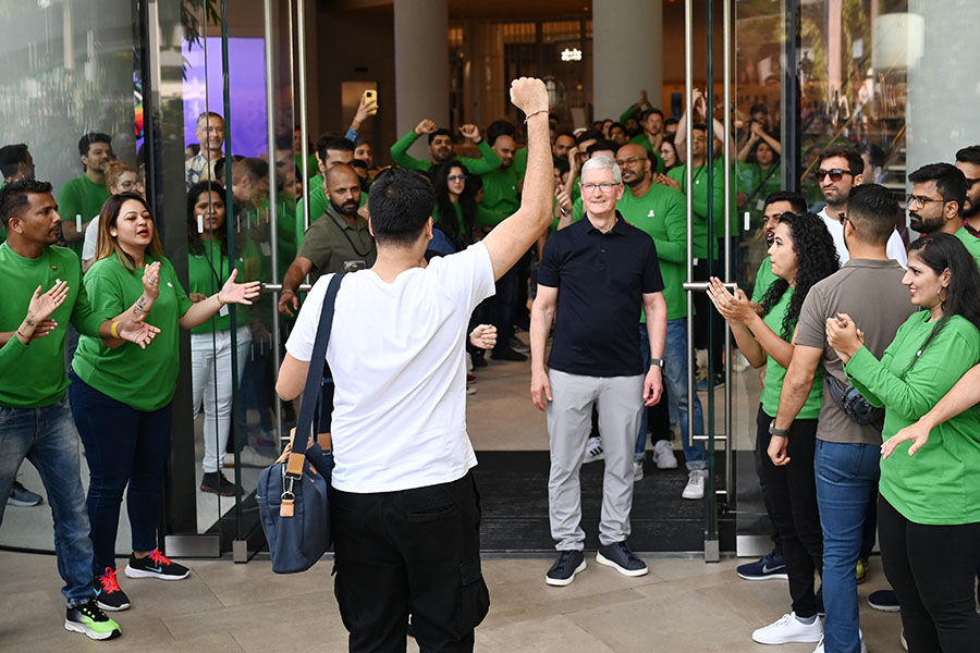 
Chief Executive Officer of Apple Tim Cook (centre R) looks on next to Apple employees cheering as a customer enters Apple's first retail store in India during its opening in Mumbai on April 18, 2023.
Image: Punit Paranjpe / AFP 