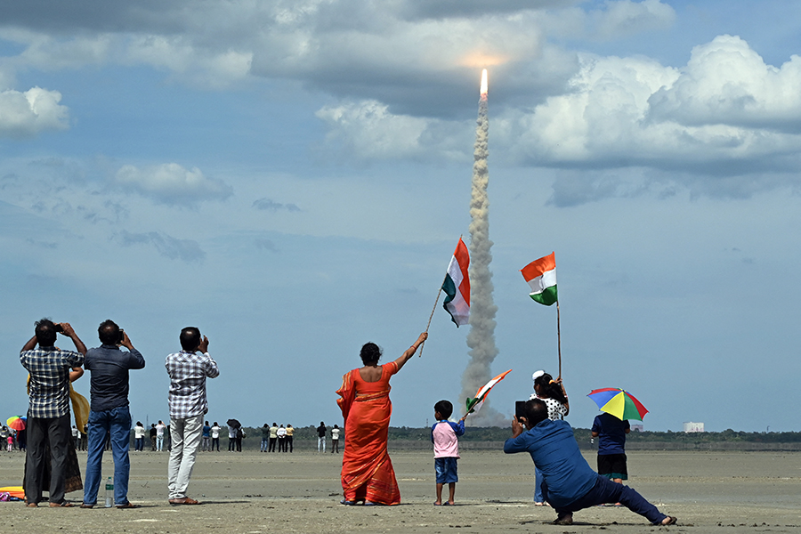 People wave Indian flags as an ISRO rocket carrying the Chandrayaan-3 spacecraft lifts off from the Satish Dhawan Space Centre in Sriharikota on July 14, 2023. Image: R.Satish BABU / AFP