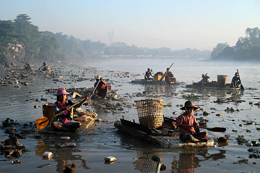 Waste collectors paddling polystyrene boats as they look for plastic and glass to recycle in Pazundaung Creek in Yangon. Image: Sai Aung Main / AFP©