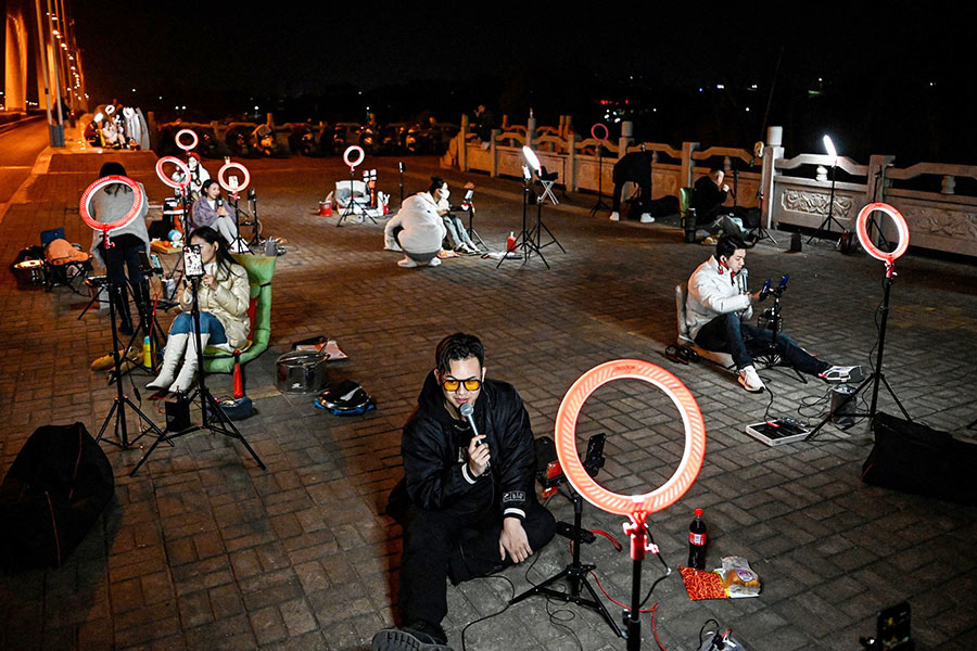 Outdoor livestreamers singing and chatting with the audiences through their mobile phones on an overpass bridge at night in Guilin
Image: Jade Gao / AFP©