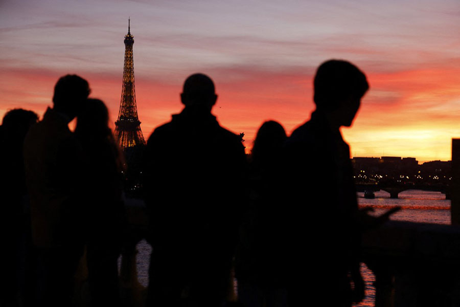 Tourists watch the Eiffel tower at sunset in Paris. Image Ludovic Marin/ AFP 
