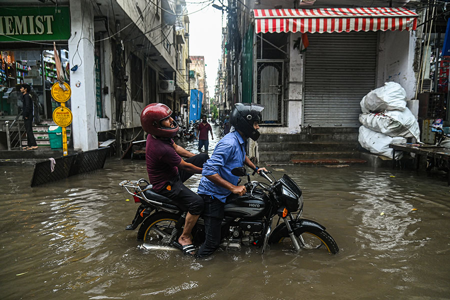 A man rides his bike through a flooded street after heavy rains lashed New Delhi. Image: Kabir Jhangiani/NurPhoto via Getty Images