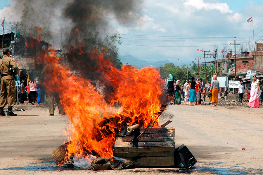 Onlookers stand near a fire started on a street in Moreh town in the northeastern Indian state of Manipur June 12, 2007; Image: Reuters