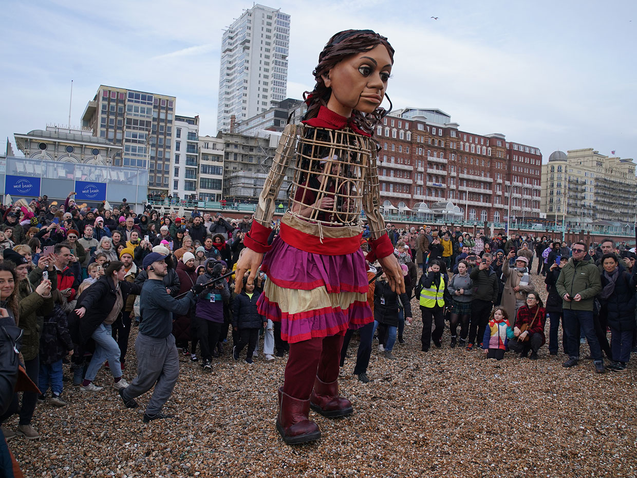 Little Amal, a 3.5 metre-tall giant puppet representing a ten-year-old Syrian refugee child, leads an early evening walk along Brighton Beach, UK, on March 30, 2023.