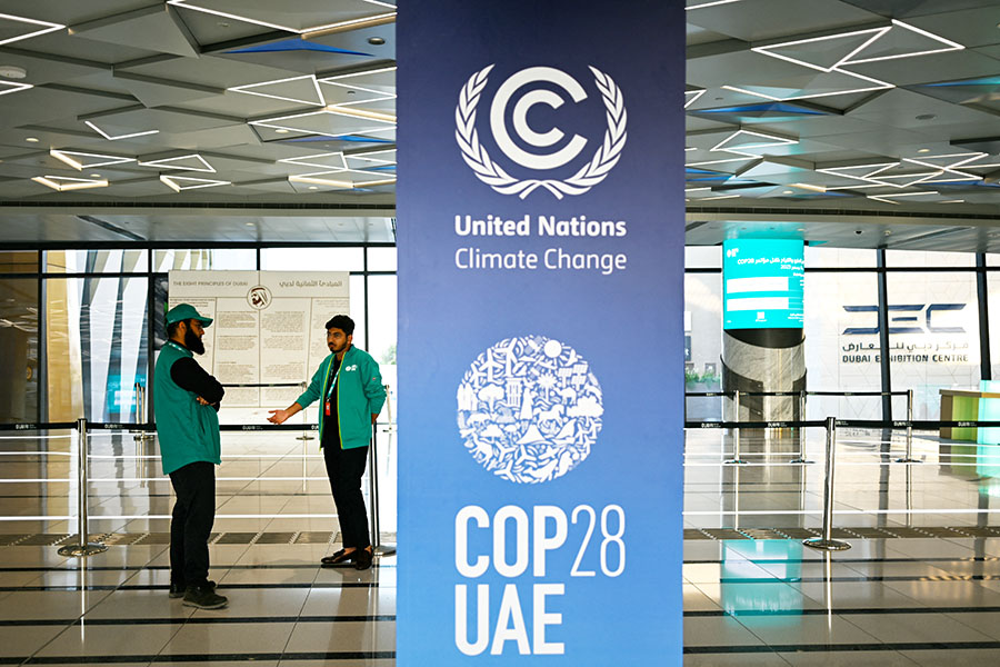 Men stand near a COP28 sign in a metro station in Dubai on November 28, 2023, ahead of the United Nations climate summit. - The UN chief urged world leaders to take decisive action to tackle ever-worsening climate change when they gather at the COP28 summit in Dubai starting this week. 
Image: Jewel Samad / AFP 