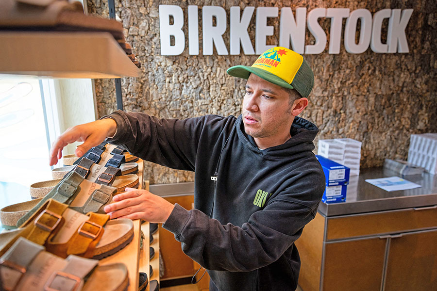 Employee Mo Soto arranges a shelf at a Birkenstock store on October 10, 2023 in Venice, California. German footwear company Birkenstock is reportedly planning to offer 32.3 million shares priced at  to , and is expected to attain a valuation of .2 billion.  Image: Ethan Swope/Getty Images/AFP  