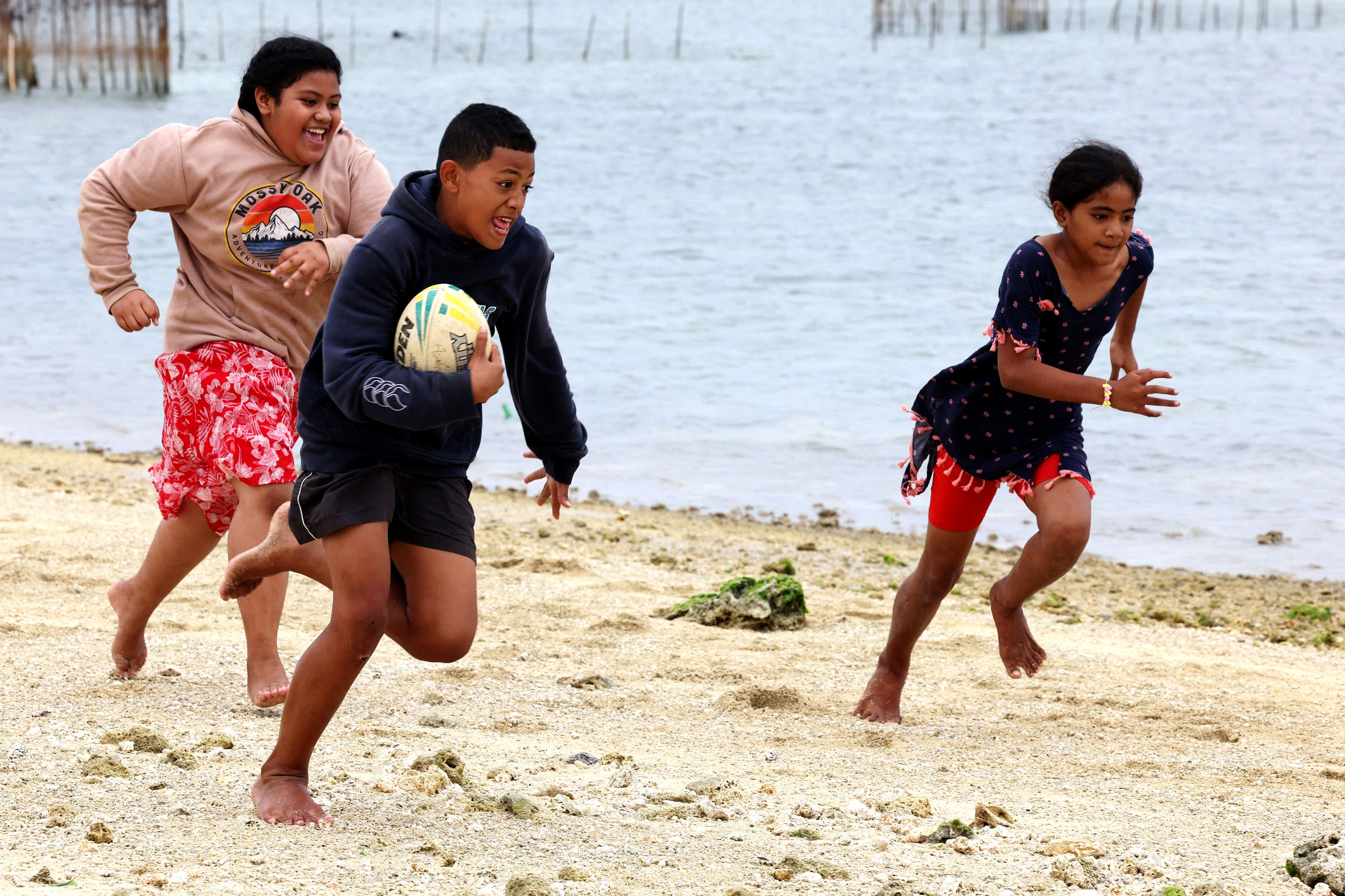 Lesieli, Siua and Sisi play a game of touch rugby by the beach at Popua on July 20, 2023, in Nuku’alofa while their families are fishing on the reef.
Image: Nuku Alofa, Tonga 