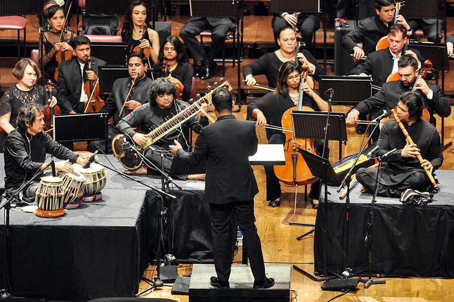 Zakir Hussain (on the tabla), Niladri Kumar (on the sitar), and Rakesh Chaurasia (on the flute) perform a triple concerto, composed by Hussain, along with the Symphony Orchestra of India led by conductor Alpesh Chauhan (standing) at the NCPA, Mumbai. The concerto will go on a three-city tour of the UK in November-December. Image: Courtesy NCPA 