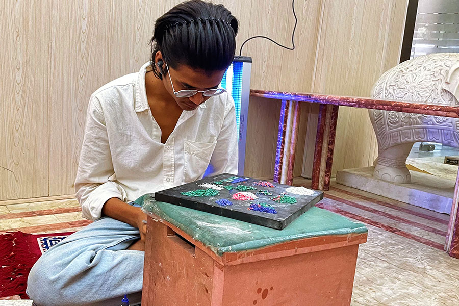 Mohammed Zaid meticulously arranges the small pieces of semi-precious stones, preparing them for adhesion onto the intricate design. Image: Veidehi Gite 