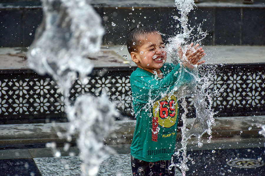 A boy seen cooling off with fountain water on a scorching summer day. Kashmir valley experienced a significant rise in temperatures with several areas recording the highest temperatures in decades. The Meteorological Department predicted the continuation of the heatwave in the next month too. (Photo by Saqib Majeed/SOPA Images/LightRocket via Getty Images)